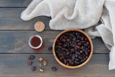 Kuru gül kalçalarının üst görüntüsü ahşap kasede yatar ve gül kalçası standından sıcak vitamin içeceği, etrafta yün tekstil yatar.. İyileşmek için soğuk mevsimde sağlıklı bir içecek..