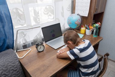 Okul çocuğu çok yorgun ve online ders sırasında dizüstü bilgisayar başında uyuyor. Evde eğitim kavramı. Öğrenciler çok fazla ödev yapmaktan yoruldu.. 