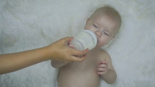 Close Six Months Old Boy Lies Bed Eats Milk Bottle — Stock Video