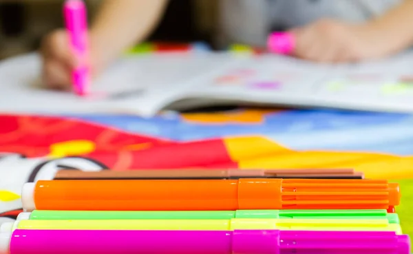 Close Up a homeschooling a first grade student doing homework with a notebook and felt-tip pens at home.