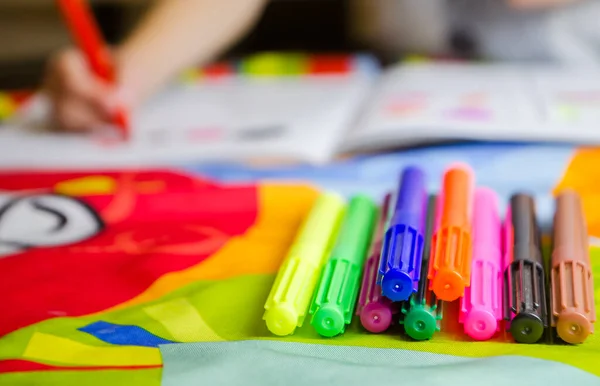 Homeschooling a first grade student doing homework with a notebook and felt-tip pens at home.