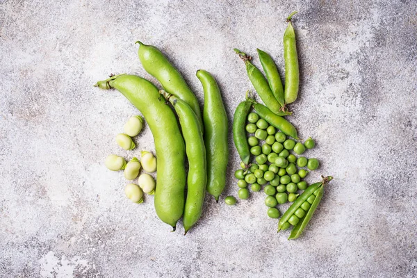 Frische grüne Erbsen und Bohnen auf hellem Hintergrund — Stockfoto