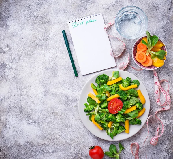 Diyet planı. Sağlıklı sebze salatası, temiz su ve ölçüm bandı. Üstten Görünüm