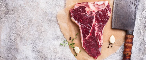 Raw T-bone steak with butchers knife