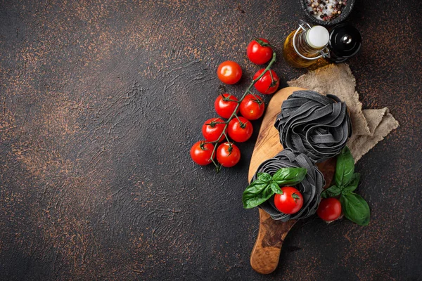 Black uncooked pasta  with tomato and basil — Stock Photo, Image