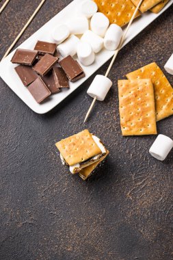 Ev yapımı s'mores kraker, şekerleme ve çikolata koyu arka plan üzerinde