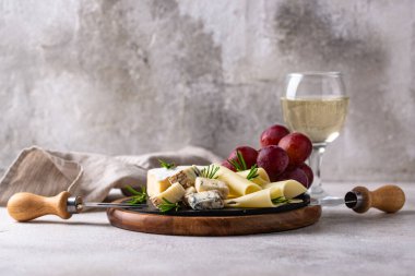 Bir bardak şarap, değişik türde yumuşak peynir ve üzümler.