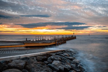 Small pier extending into silky smooth ocean at sunset - long exposure seascape clipart