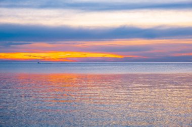 Ufukta küçük bir balıkçı teknesiyle gün batımının en düşük deniz manzarası.