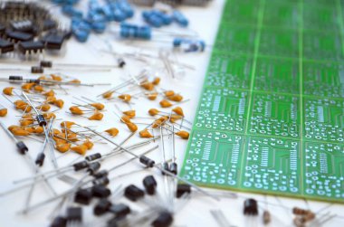 Yeşil elektronik devre kartının yanında düzenlenmiş elektronik bileşenler grubu