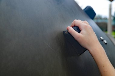 Çocuk eli, oyun bahçesindeki kaya tırmanma duvarına tutunuyor.