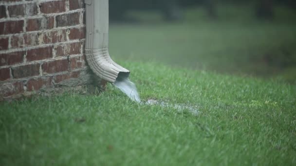Canalón de trabajo en una casa de ladrillo con agua corriente en la hierba durante la tormenta de lluvia — Vídeo de stock