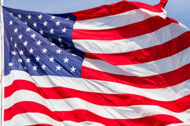 Rüzgarda dalgalanan büyük güzel Amerikan bayrağı, canlı kırmızı beyaz ve mavi renkler, çerçeveyi dolduruyor..