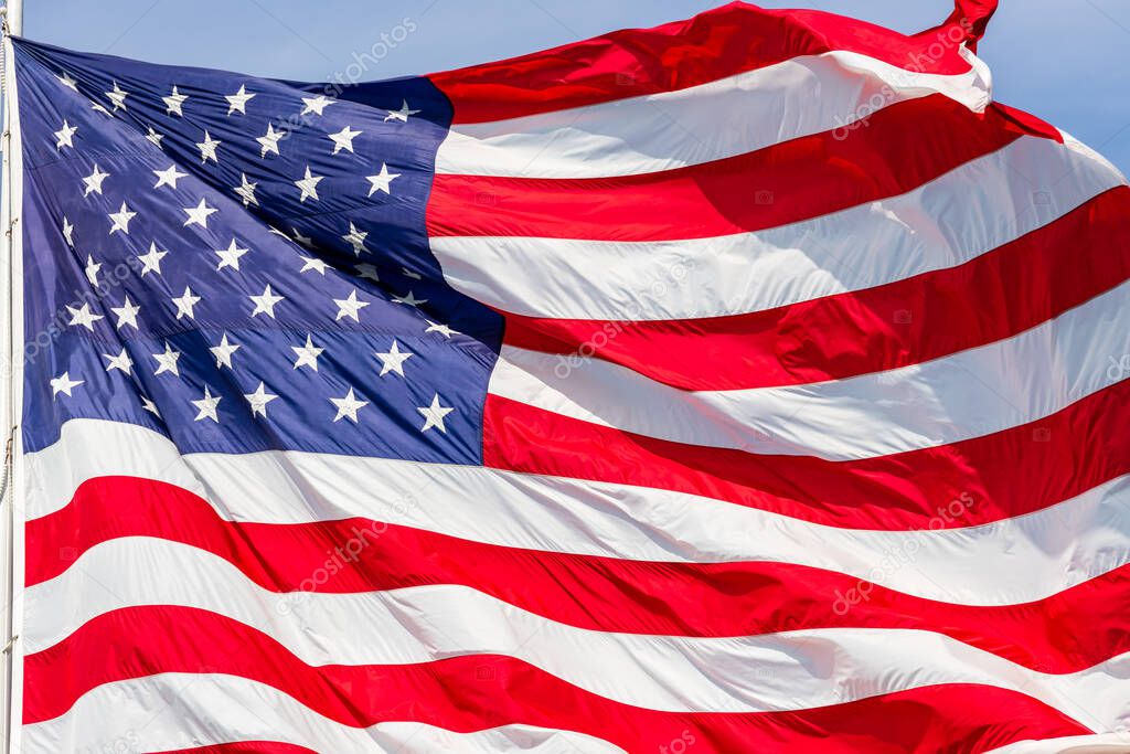 Large beautiful American flag waving in the wind, with vibrant red white and blue colors, filling the frame.