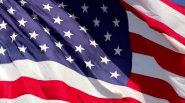Rüzgarda dalgalanan Amerikan bayrağı, canlı kırmızı beyaz ve mavi renkler çerçeveyi tamamen dolduruyor.