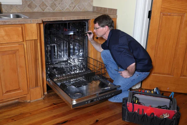 Appliance repair technician works on broken dishwasher