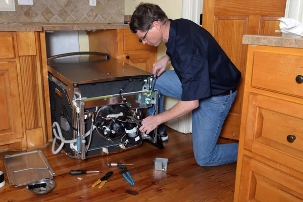 Appliance repair technician works on broken dishwasher