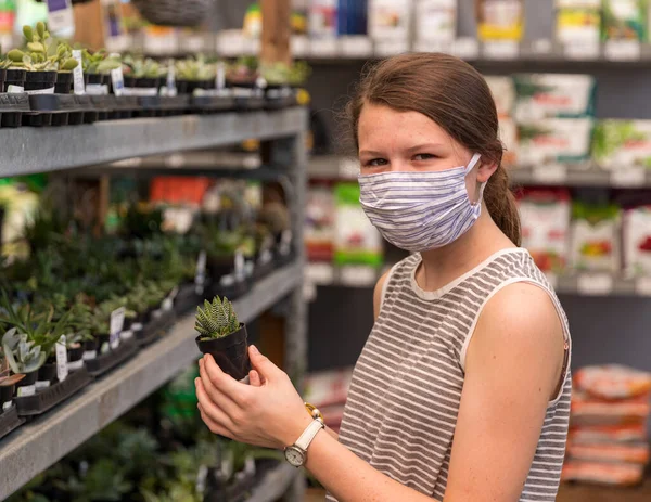 A shopper wears a face mask while pickng out plants at a store during a pandemic