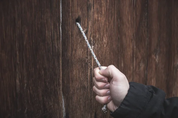 Hand and rope with wooden door