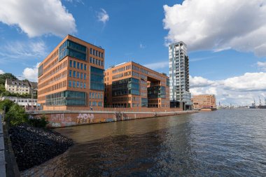 Almanya 'nın Elbe nehri kıyısında Hamburg limanında güzel bulutları ve mavi gökyüzü olan modern binalar.