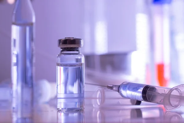 ampoule, glass vials and a medical syringe with a coronavirus vaccine on a blue background