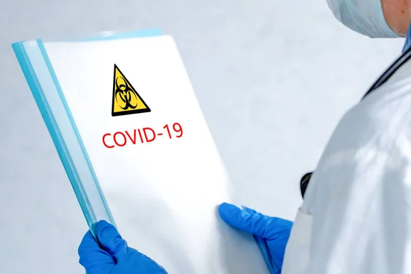 Coronavirüs salgınıyla ilgili materyalleri içeren bir klasörü olan doktor COVID-19