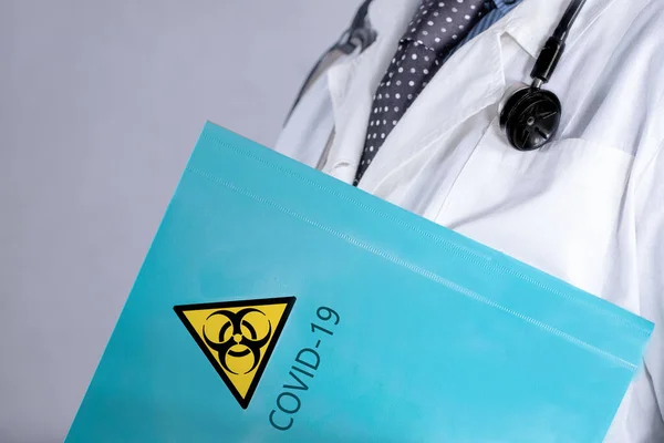 Coronavirüs salgınıyla ilgili materyalleri içeren bir klasörü olan doktor COVID-19