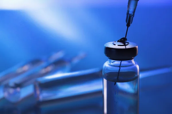 ampoule, glass vials and a medical syringe with a coronavirus vaccine on a blue background