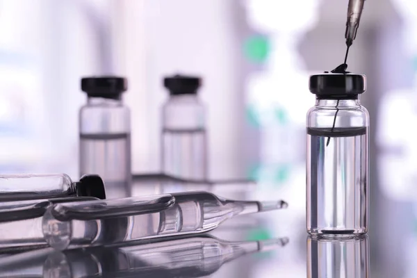 ampoule, glass vials and a medical syringe with a coronavirus vaccine on a blue background