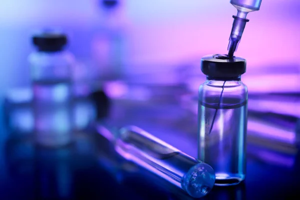 ampoule, glass vials and a medical syringe with a coronavirus vaccine on a blue background