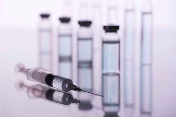 ampoule, glass vials and a medical syringe with a coronavirus vaccine on a blue background