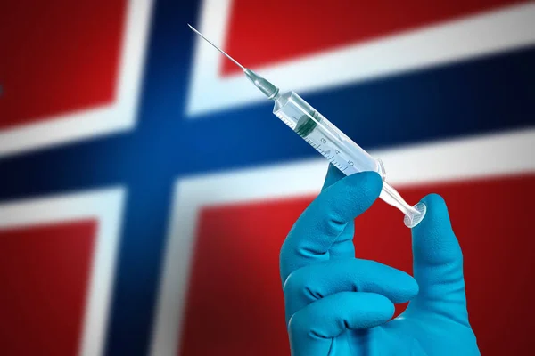 Koronavirüs salgınına karşı savaşın. Norveç bayrağının arka planında COVID-19 'un tedavisi için eldiven ve aşı ile doktorun eli. Norveç 'te grip aşısı