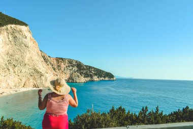 Yunanistan 'da Porto Katskiki plajında kırmızı elbiseli ve fötr şapkalı güzel bir kadın.