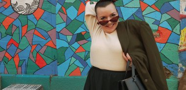 Arkaplanda graffiti olan, duvarın yanında poz veren şık bir model. 