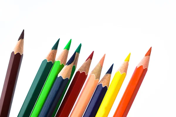 白い紙の背景に散在する9つの異なる色の木の鉛筆のクレヨン — ストック写真