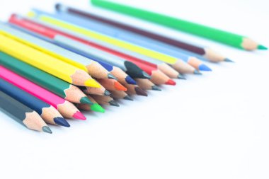 Beyaz bir kağıda saçılmış bir sürü farklı renkte tahta kalem kalemi.