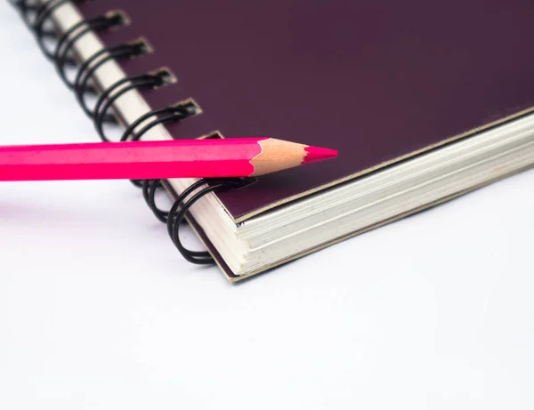 紫色の螺旋状のノートブックペーパーの上に置かれたピンク色の木製の鉛筆クレヨン — ストック写真