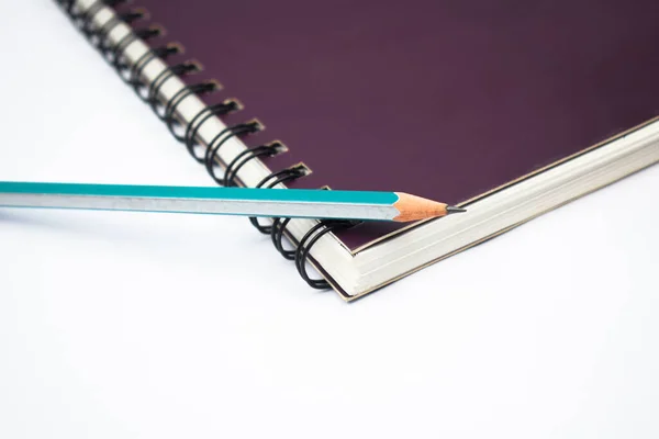 紫色の螺旋状のノートブックペーパーの上に置かれた青い色の木製の鉛筆クレヨン — ストック写真