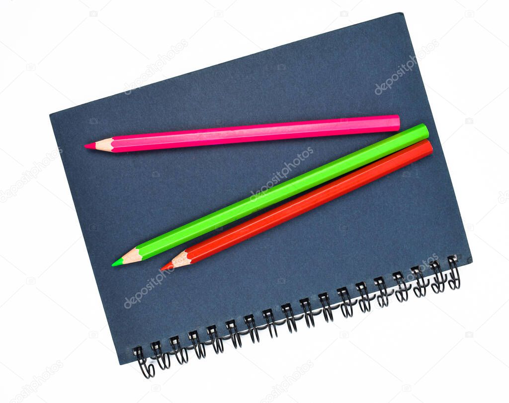 Three different colored wood pencil crayon placed on top of a blue paper diary