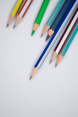 Beyaz bir kağıdın üzerine farklı renkte tahta kalemler yerleştirilmiş.