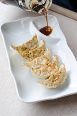 Beyaz tabakta soslu gyoza.