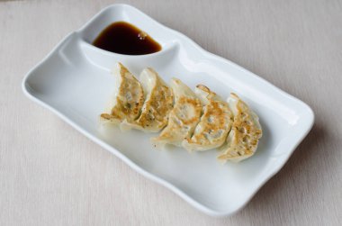 Beyaz tabakta soslu gyoza.