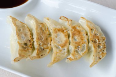 Beyaz tabakta soslu gyoza.
