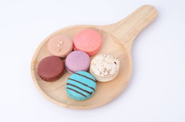 Beyaz arka plandaki ahşap masada renkli makaronlar.