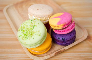 Ahşap tabakta renkli makaronlar. Öğleden sonra çayında tatlı.