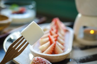 Çilek dilimi ve marhmellow seti ve kahve tabağında çikolatalı fondü.