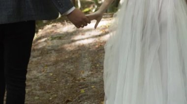 Sonbahar ormanının ortasında, yol üzerinde kahverengi ve yeşil yapraklar olan siyah pantolonlu bir adam sapın yanından geçiyor. Beyaz, gür, uzun elbiseli bir kızla. Adamın elinde bir nişan yüzüğü var.