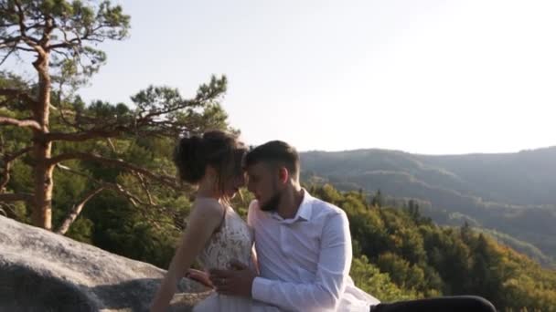 Νεαρό Παντρεμένο Ζευγάρι Κάθεται Ψηλά Στα Βουνά Ένα Μεγάλο Βράχο — Αρχείο Βίντεο