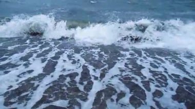 Deniz fırtınası, kumlu sahilde büyük dalgalar. Dalgalarda köpük. Sahilden deniz fırtınasına bak. HD video