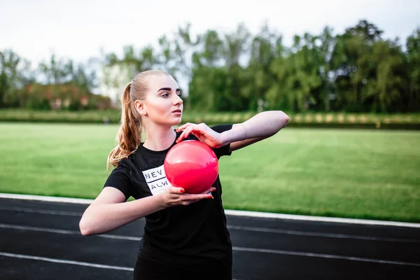 Healthy sports lifestyle. Athletic young woman in a sports dress doing fitness exercises. Fitness woman at the stadium. Young girl holding a ball. The ball in the hands of a girl. Sport.